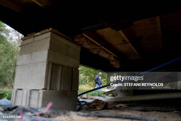 Chase Hays is seen through the damaged foundation of his home as he walks in front of his house in Lost Creek, Kentucky, on September 29, 2022. -...