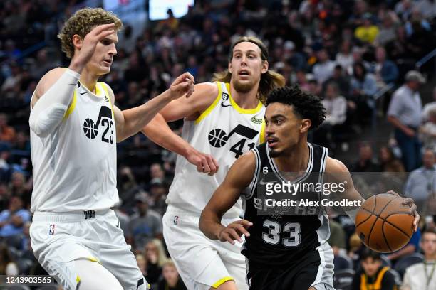 Tre Jones of the San Antonio Spurs drives under Kelly Olynyk and Lauri Markkanen of the Utah Jazz during a game at Vivint Arena on October 11, 2022...