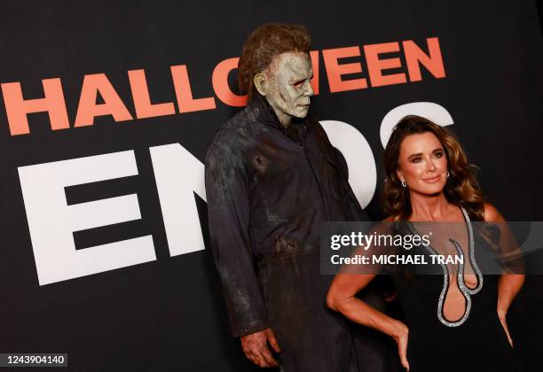 Person dressed as the character Michael Myers stands behind US actress Kyle Richards as she arrives for the premiere of "Halloween Ends" at the TCL...