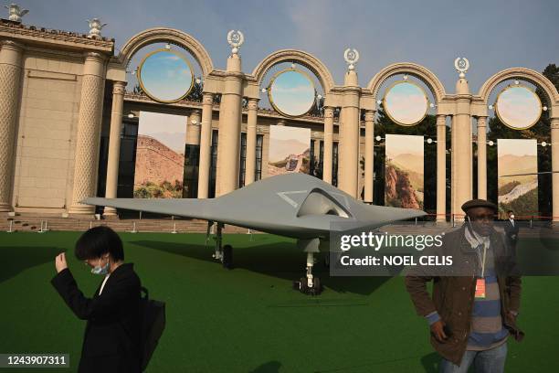 People stand in front of a GJ-11 stealth combat drone on display at the Beijing Exhibition Center, where an exhibition entitled "Forging Ahead in the...