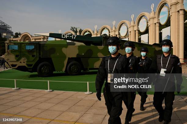 Security personnel march in front of a Dongfeng-17 medium-range ballistic missile and its mobile launcher on display at the Beijing Exhibition...