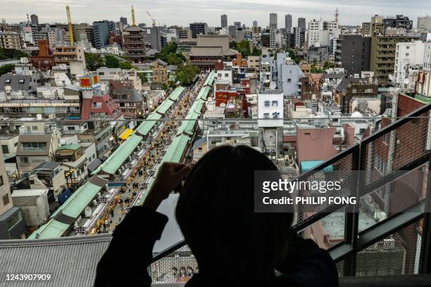 Visitor takes pictures of Sensoji Temple from the observation area of a tourist information centre in Taito district of Tokyo on October 12, 2022.