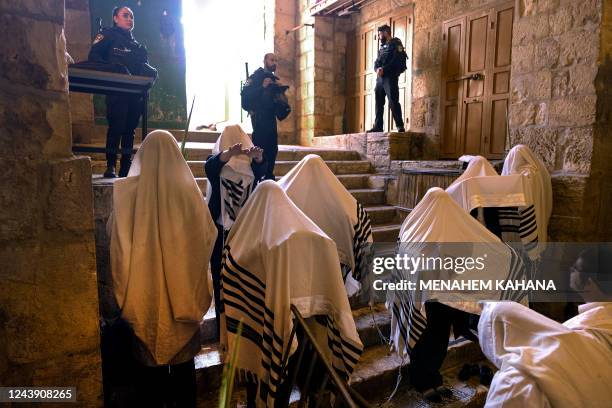 Israeli police secure the area as ultra-Orthodox Jewish men wearing traditional Jewish prayer shawls known as Tallit pray at the Cotton Merchants...