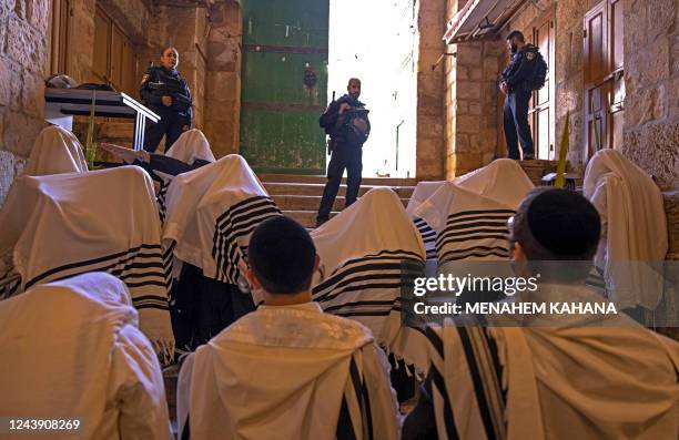 Israeli police secure the area as ultra-Orthodox Jewish men wearing traditional Jewish prayer shawls known as Tallit pray at the Cotton Merchants...