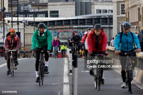 Cyclists ride across London Bridge during rush hour in central London on October 12, 2022.