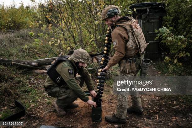 Soldiers of Ukraine's 5th Regiment of Assault Infantry put ammunition into a crate before setting a US-made MK-19 automatic grenade launcher towards...