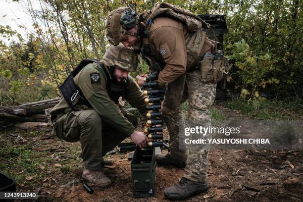 Soldiers of Ukraine's 5th Regiment of Assault Infantry put ammunition into a crate before setting a US-made MK-19 automatic grenade launcher towards...