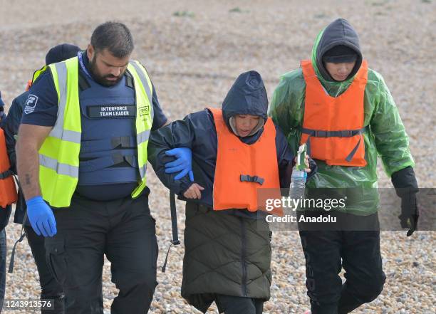 Migrants being helped ashore from a packed lifeboat by the border force and police officers are taken to Dungeness beach in Kent, United Kingdom on...