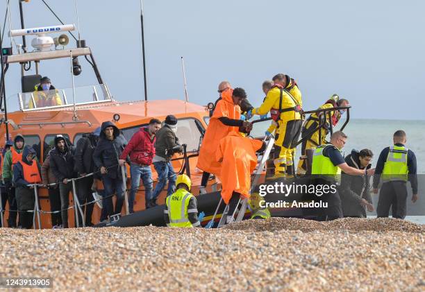 Migrants being helped ashore from a packed lifeboat by the border force and police officers are taken to Dungeness beach in Kent, United Kingdom on...