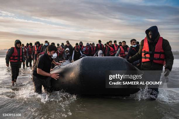 Migrants move a smuggling boat into the water as they embark on the beach of Gravelines, near Dunkirk, northern France on October 12 in an attempt to...