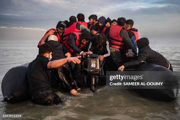 Migrants try to start an outboard engine after boarding a smuggler's boat on the beach of Gravelines, near Dunkirk, northern France on October 12 in...