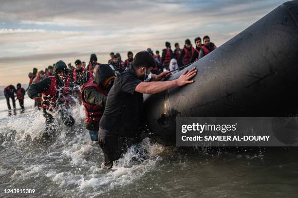 Migrants push a smuggling boat into the water as they embark on the beach of Gravelines, near Dunkirk, northern France on October 12 in an attempt to...