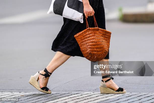 Passerby wears a brown wooden large bag, platform shoes with straw soles, on June 03, 2020 in Paris, France.