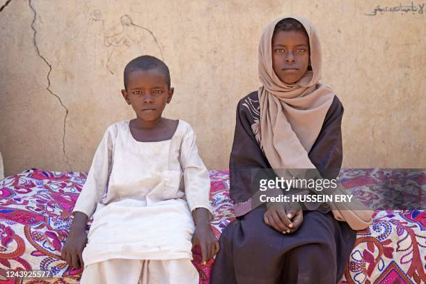 Zahra Hussein , a nine-year-old Sudanese girl who dropped out of school for financial reasons, poses for a picture with her brother at their home in...