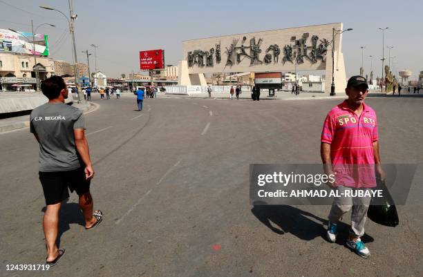 Iraqis walk in a street after security forces blocked a road leading to the Green Zone in Baghdad on October 13, 2022 as lawmakers gather for their...