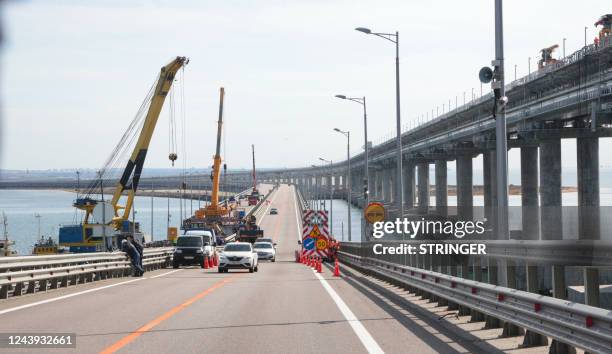 This picture taken on October 13, 2022 shows workers restoring damaged parts of the Kerch Bridge that links Crimea to Russia, which was hit by a...