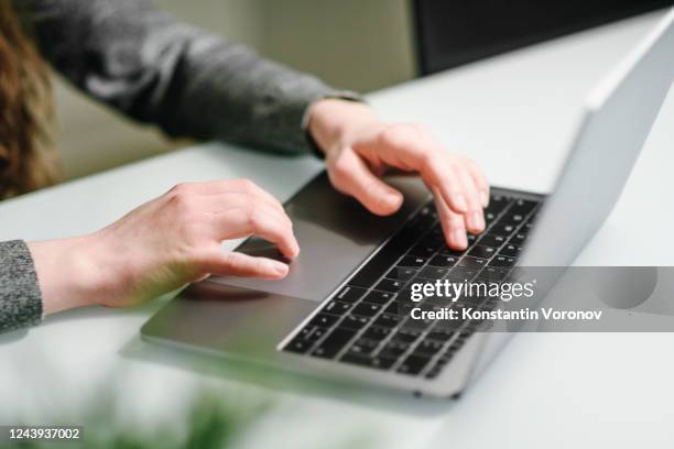 hands of a young woman typing text on the laptop keyboard. gray clothes. woman working at home office hand on keyboard close up. - touch pad stock pictures, royalty-free photos & images