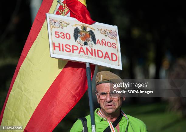 An elderly man holds a Spanish flag with a placard with the pre-constitutional eagle during the Hispanic Day parade. October 12, Spain National Day....