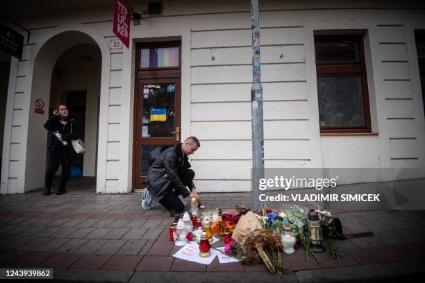 Man places a candle on the pavement at Zamocka Street in Bratislava on October 13, 2022 after a 'radicalised teenager' shot dead two men at the...