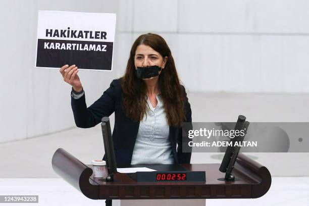 Peoples' Democratic Party's Zuleyha Gulum holds a banner "Truths cannot be obscured" as she stands with a covered mouth at the Turkish Grand National...