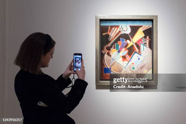 Staff member takes a picture of a painting titled 'Tiefes Braun' by Wassily Kandinsky during a photo call to present the highlights from the estate...