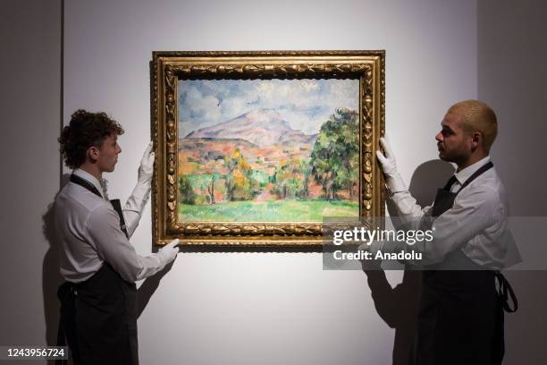 Art handlers hold a painting titled 'La montagne Sainte-Victoire' by Paul Cezanne during a photo call to present the highlights from the estate of...