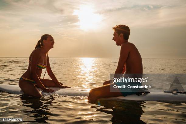 海のサーフボードに座っている若いカップル - sitting on surfboard ストックフォトと画像