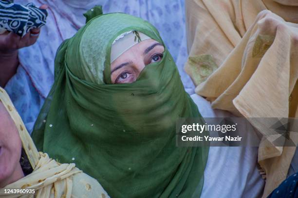 Kashmiri Muslim woman devotee looks towards a cleric displaying the holy relic believed to be the whisker from the beard of the Prophet Mohammed, at...