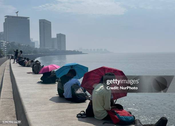 Couples use umbrellas to protect themselves from the sun, as they sit on the promenade at Marine drive, on a hot day in Mumbai, India, 14 October,...