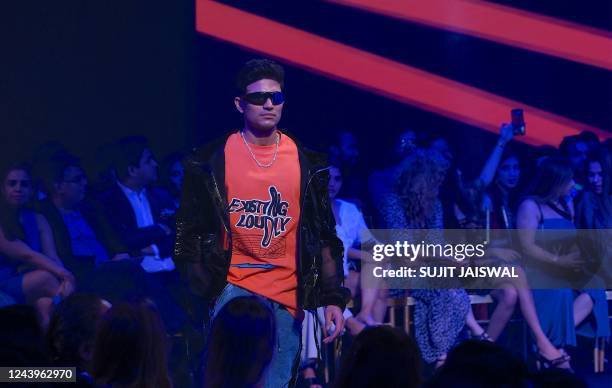 Indian international cricketer Shubman Gill presents a creation by designer Kanika Goyal during the FDCI X Lakme Fashion Week in Mumbai on October...