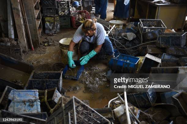Woman cleans the mud inside a shop after a landslide during heavy rains in Las Tejerias, Aragua state, Venezuela, on October 14, 2022. - According to...