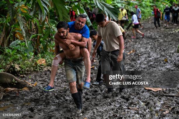 Venezuelan migrant Jesus Arias is helped by a friend as they arrive at Canaan Membrillo village, the first border control of the Darien Province in...