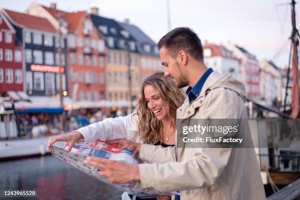 joyful couple looking at a map - map copenhagen stock pictures, royalty-free photos & images