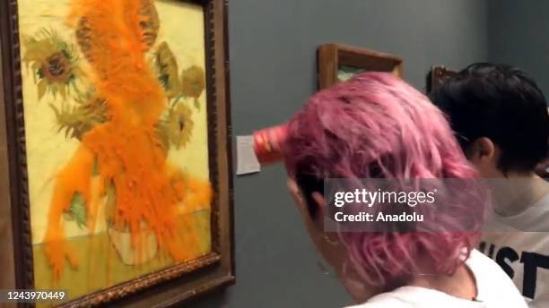 Climate protesters hold a demonstration as they throw cans of tomato soup at Vincent van Goghâs âSunflowersâ at the National Gallery in London,...