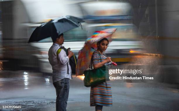 Citizens wait to cross the road during heavy rain, at Sion on October 14, 2022 in Mumbai, India. Heavy rain lashed several parts of Mumbai. The city...