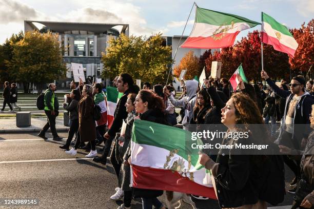 Demonstrators, some with Shah-era flags, pass by the federal chancellery during a march in solidarity with protesters in Iran on October 15, 2022 in...