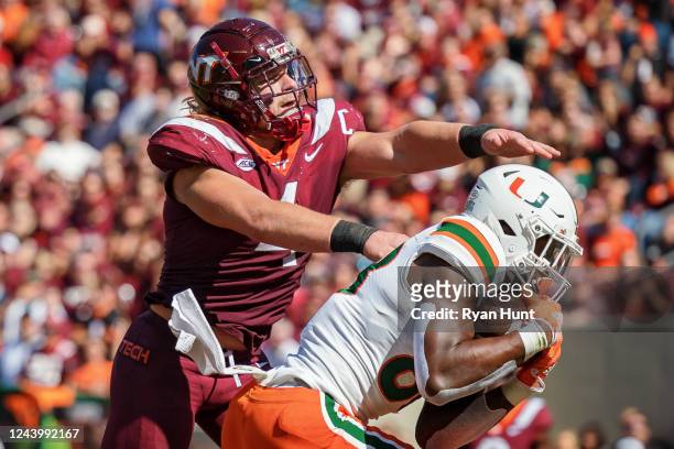 Linebacker Dax Hollifield of the Virginia Tech Hokies reaches over wide receiver Colbie Young of the Miami Hurricanes during the second quarter at...
