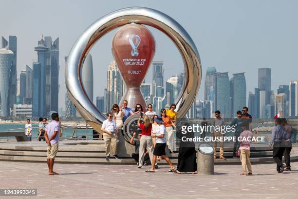 Picture taken on October 15, 2022 shows people gathering near the World Cup countdown clock in the Qatari capital Doha ahead of the FIFA 2022...