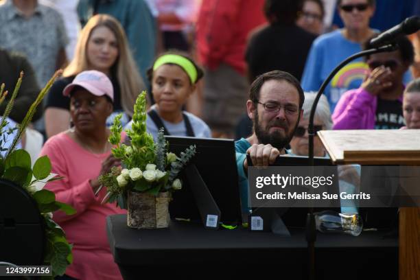 Man mourns over the image of his loved one as community members gather to comfort one another and honor 5 lives lost in a shooting in the Hedignham...