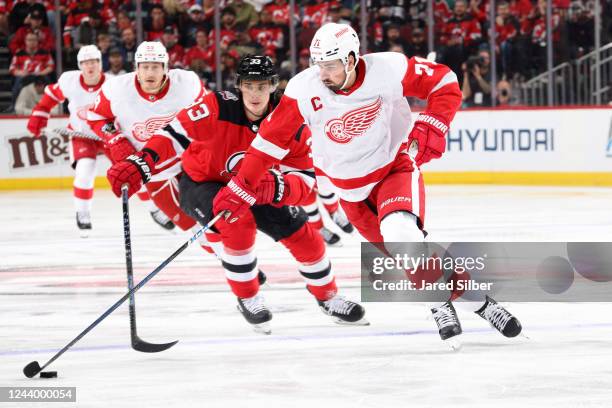 Dylan Larkin of the Detroit Red Wings skates with the puck against Ryan Graves of the New Jersey Devils at the Prudential Center on October 15, 2022...