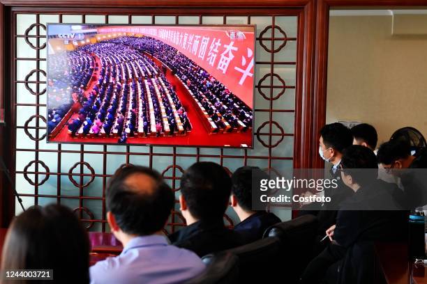 Staff members watch the opening ceremony of the 20th National Congress of the Communist Party of China in Qingdao, Shandong province, China, Oct 16,...