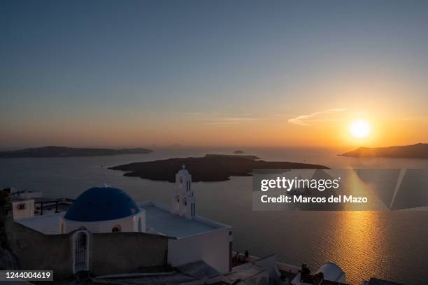 View of the sunset with The Three Bells of Fira, officially known as The Catholic Church of the Dormition, with its traditional blue dome above the...