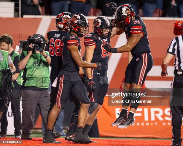 Jaren Kump, Devaughn Vele and Taniela Pututau of the Utah Utes congratulate Dalton Kincaid after he scored a touchdown against the USC Trojans during...