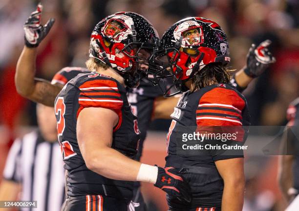 Logan Kendall of the Utah Utes celebrates with teammate Cameron Rising after he scored a touchdown against the USC Trojans during the second half of...