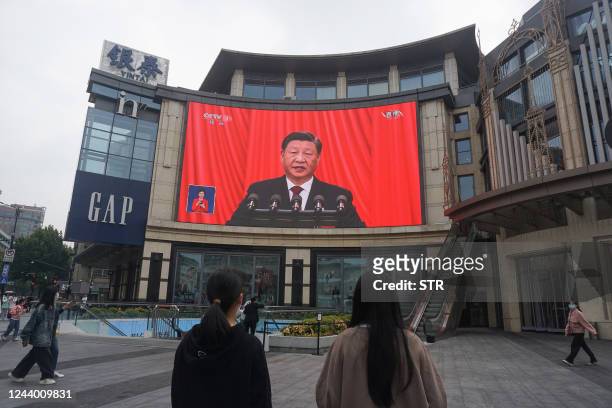 People watch an outdoor screen showing the live speech of Chinese President Xi Jinping during the opening session of the 20th Chinese Communist Party...
