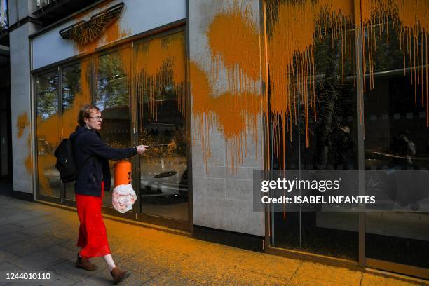 Member of the environmental activist group Just Stop Oil sprays orange paint on the window shop of the Aston Martin car show room, in central London,...