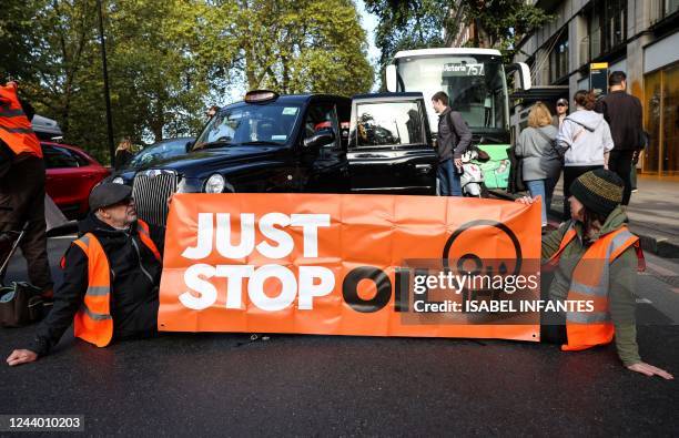 Members of the environmental activist group Just Stop Oil hold a banner as they block Park Lane, in central London, on October 16, 2022 as part of a...