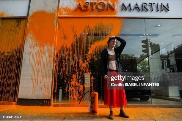 Member of the environmental activist group Just Stop Oil reacts after spraying orange paint on the window shop of the Aston Martin car show room, in...