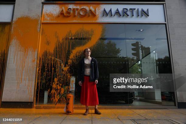Just Stop Oil demonstrator sprays an orange substance on an Aston Martin store in Mayfair on October 16, 2022 in London, England. Just Stop Oil are...