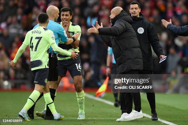 Manchester City's Spanish manager Pep Guardiola and his players surround English referee Anthony Taylor as he goes to the screen to look at a VAR...